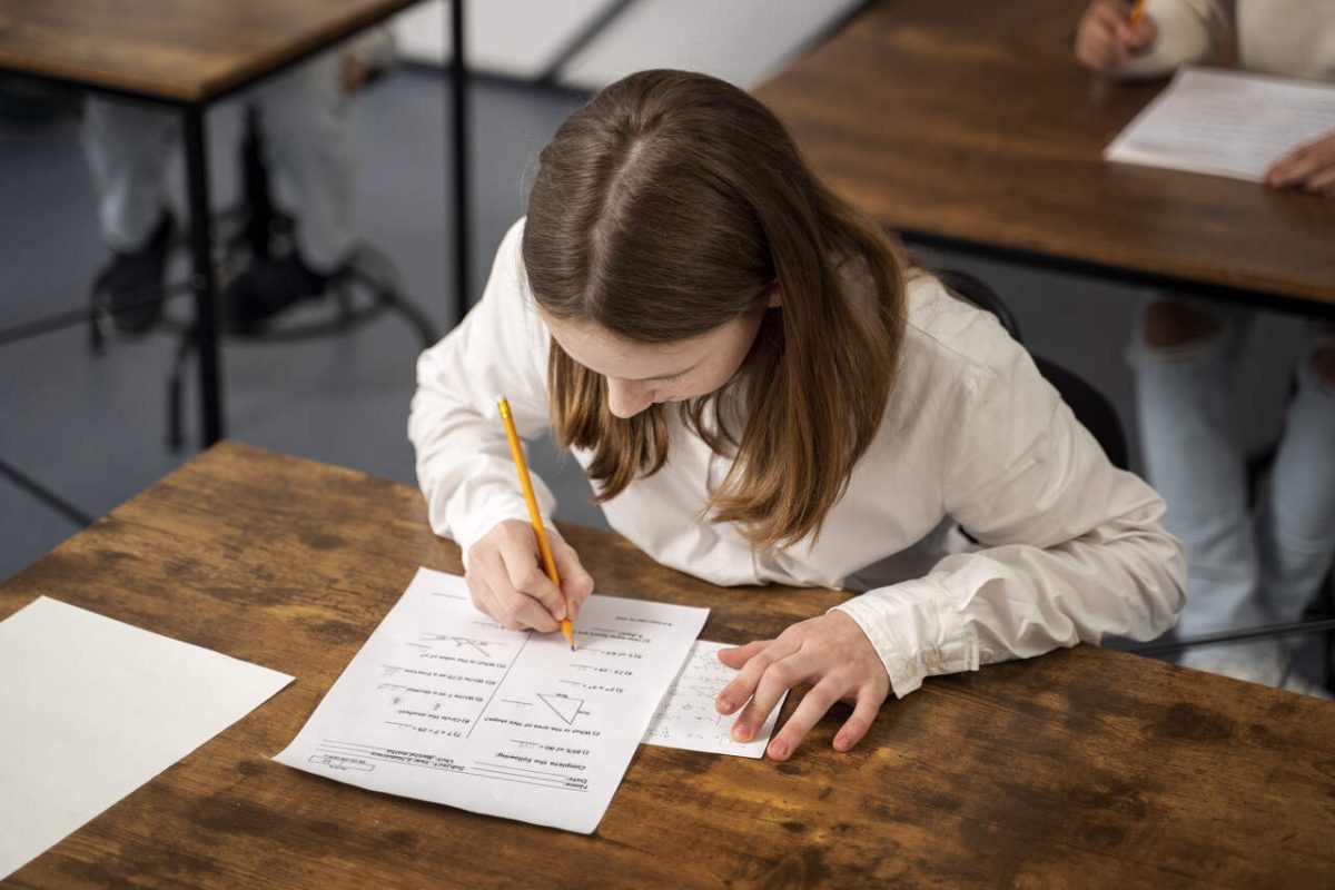 Aluna faz prova de matemática concurso público com folha e lápis