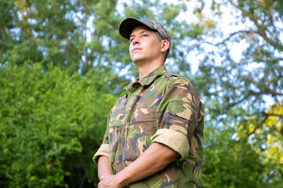 Soldado com uniforme e boina no meio da floresta