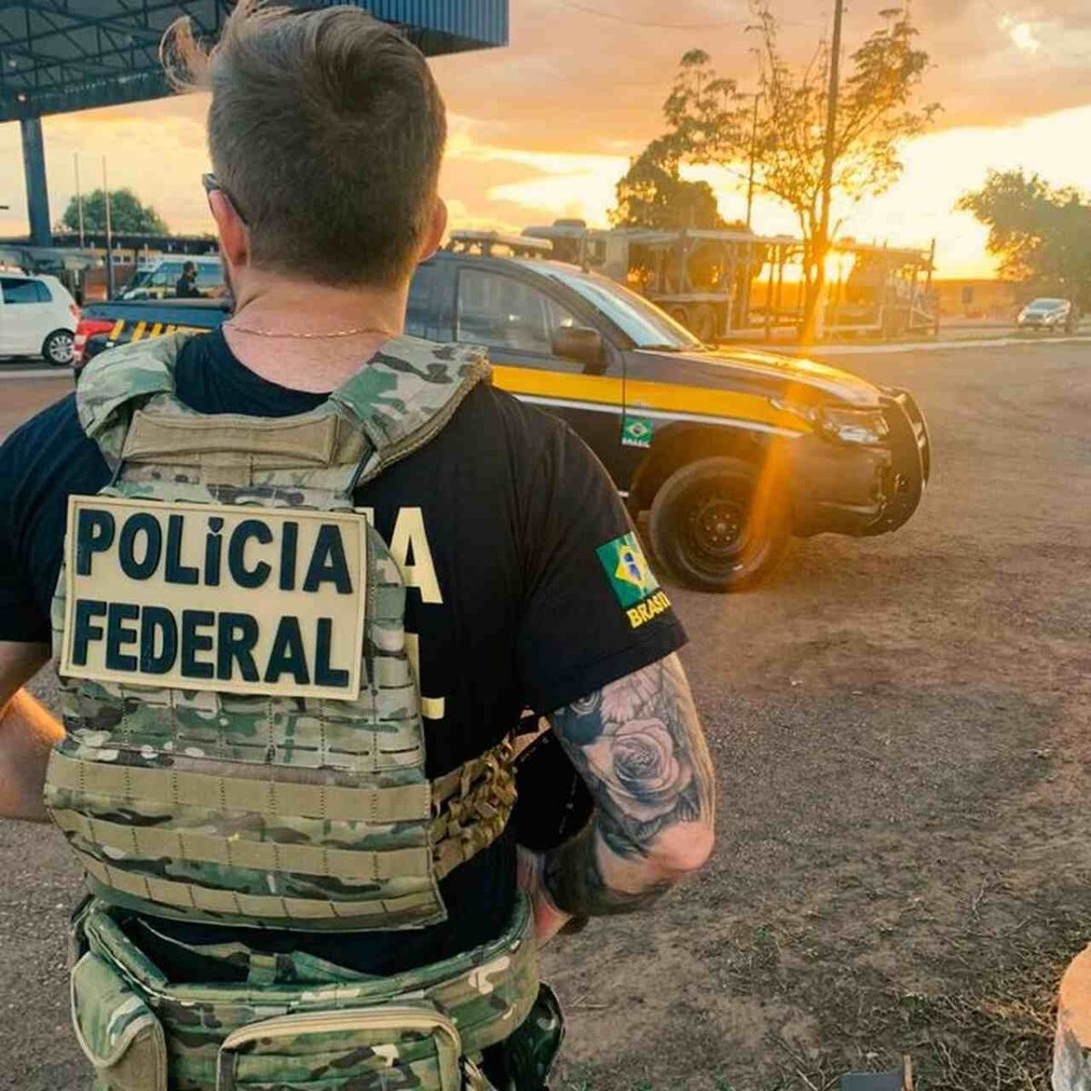Agente da Polícia Federal com colete, viatura e fuzil 