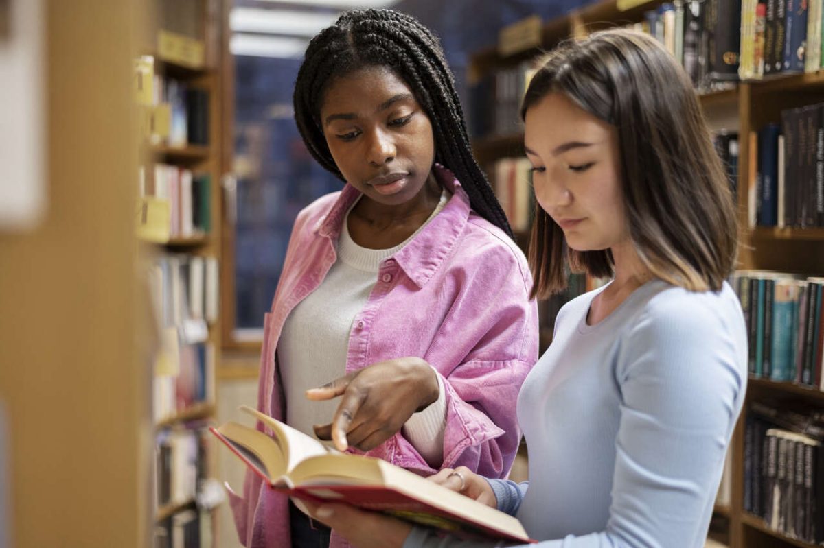 Duas mulheres estudam livro em biblioteca