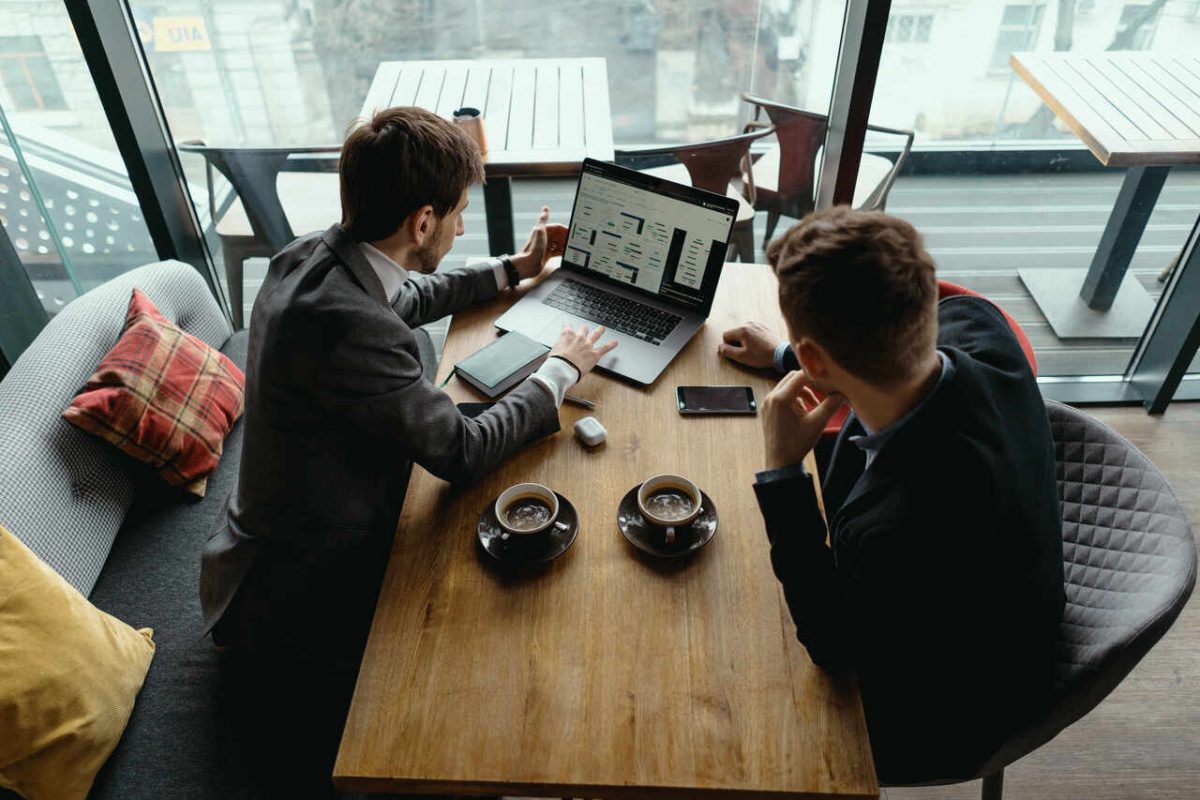 Dois homem em escritório com xícaras de café, notebooks e carteiras