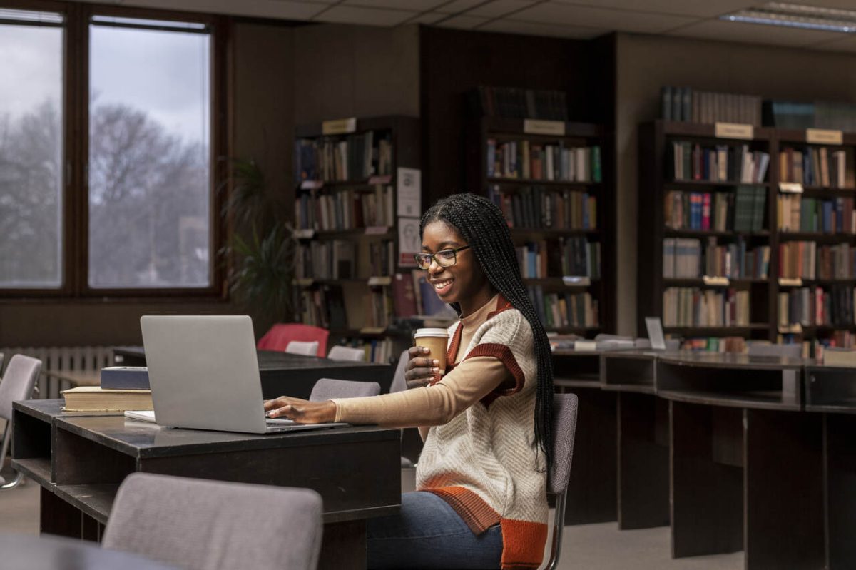 Estudante se prepara para concursos públicos com café e notebook em biblioteca