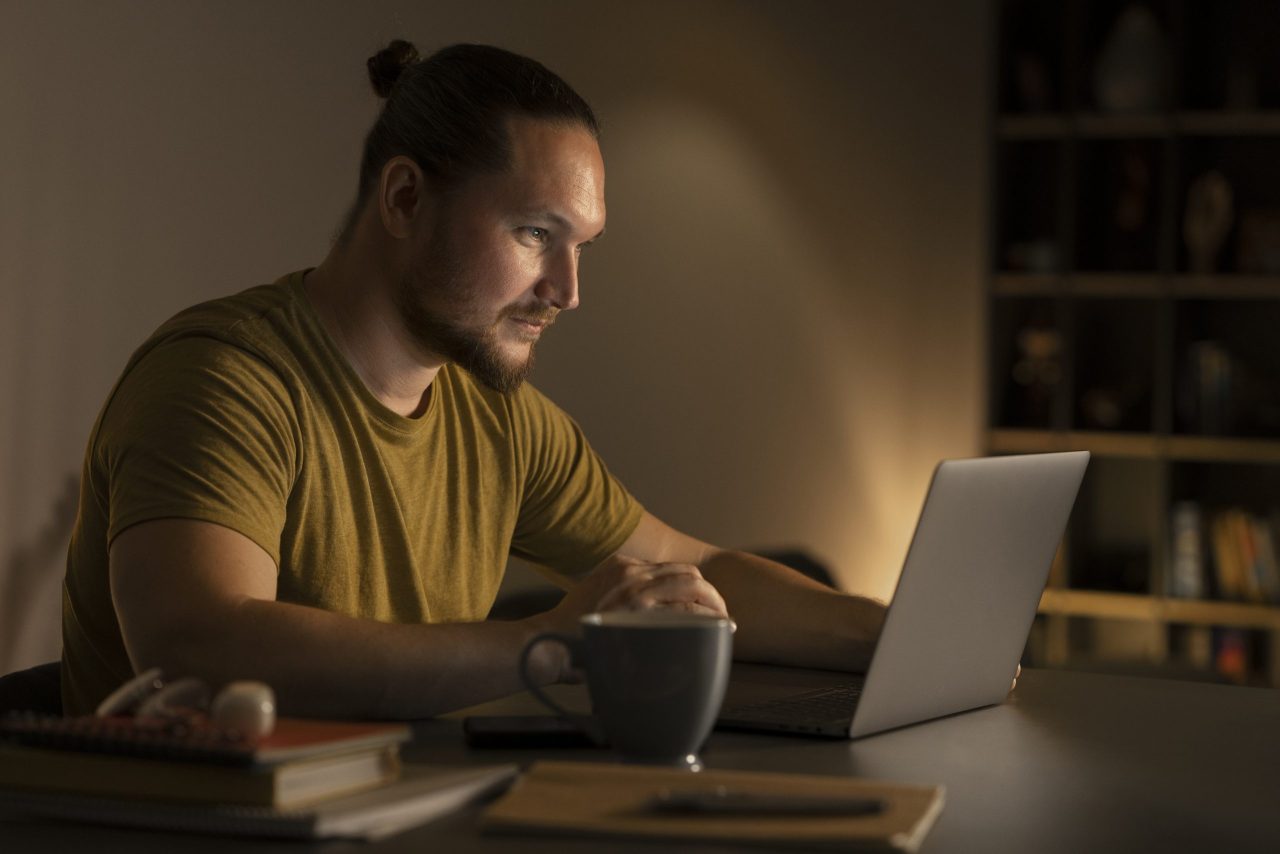 Homem estudante em quarto de estudos com xícara de café e computador