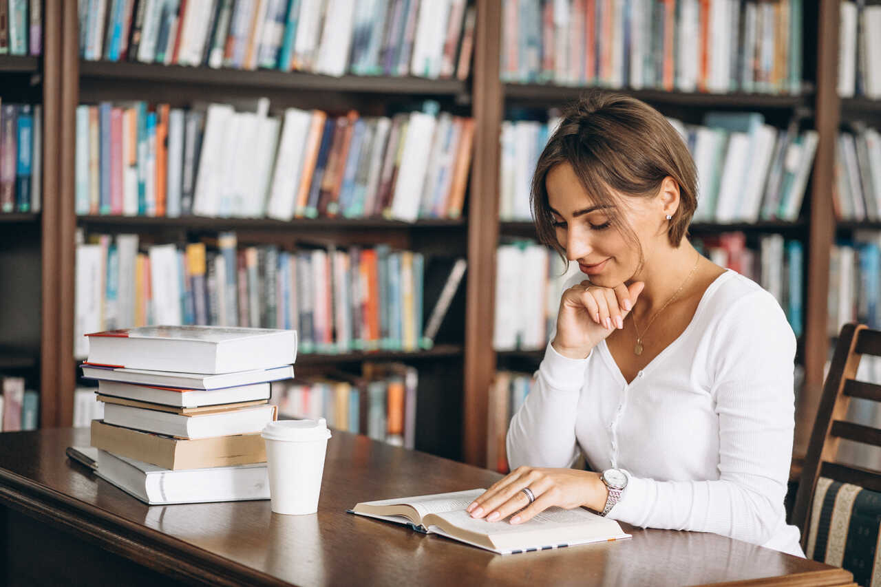 Mulher estudando em biblioteca com livros e café 