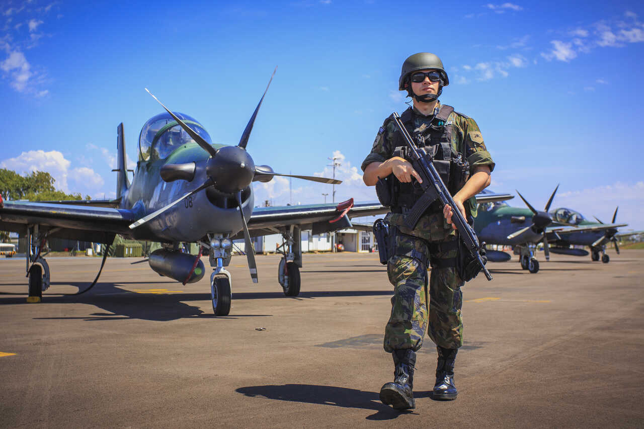 Concurso Aeronáutica 2024: sargento com fuzil e aviões FAB 