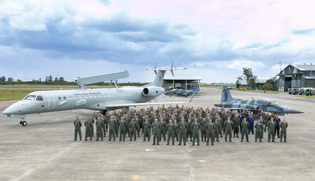 Concurso Aeronáutica 2024 com sargentos em fila de formação com aviões ao fundo 