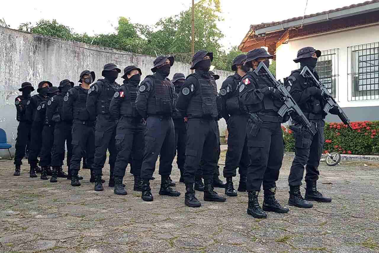 Grupo de agentes penitenciários com uniforme preto e armamento 